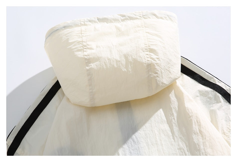 Close-up of an ivory hood and black stripe trim on a crinkled garment.