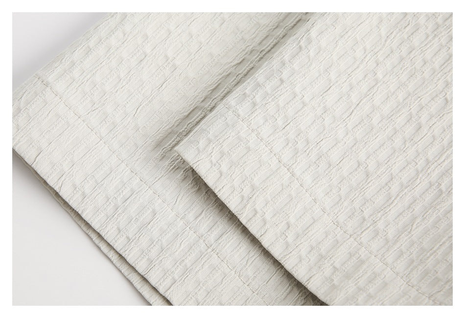 Close-up of layered ivory garment panels with visible seams and textured fabric.