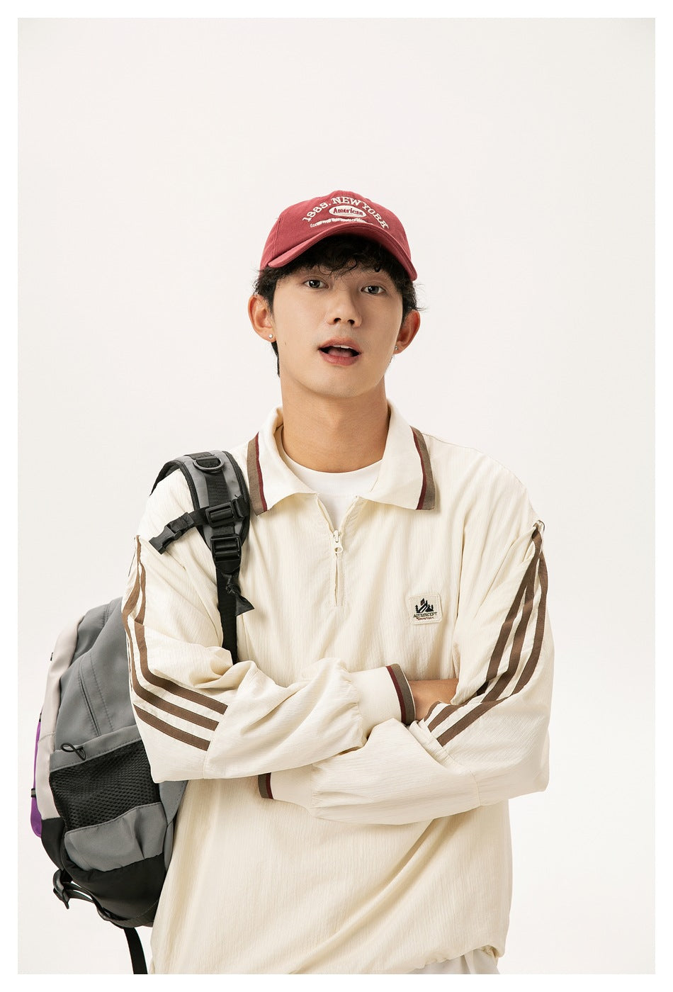 Close view of a model wearing a cream quarter-zip collared top with brown striped sleeves and contrasting trim.