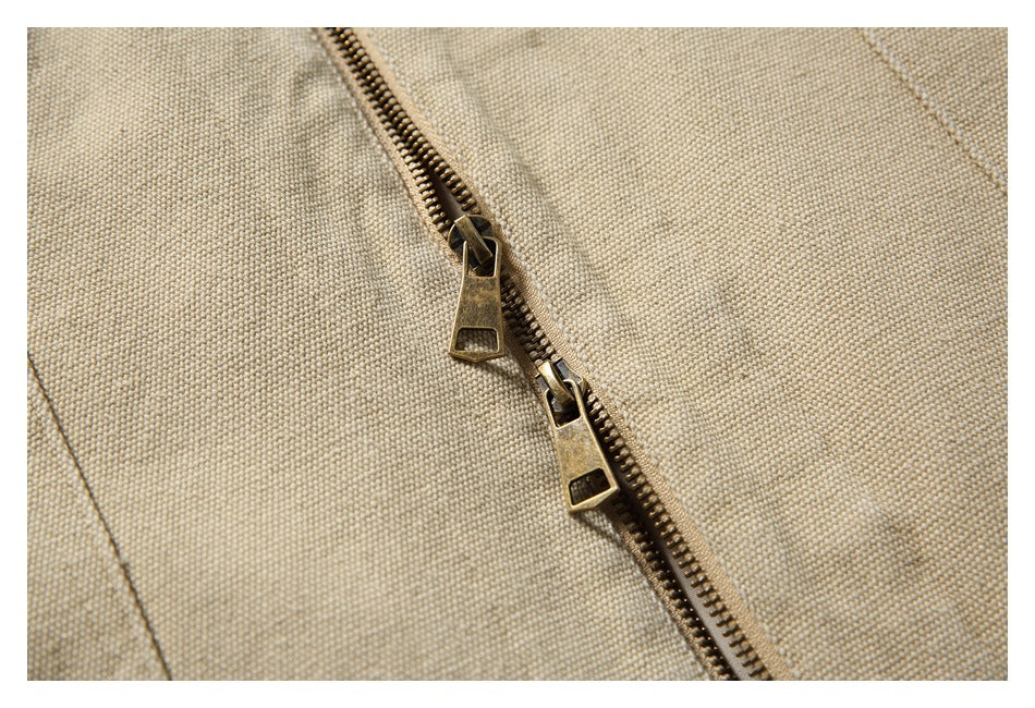 Close-up of a beige jacket’s bronze two-way zipper and textured fabric.