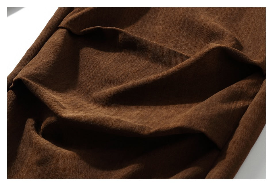 Close-up of dark brown garment fabric arranged in soft folds.