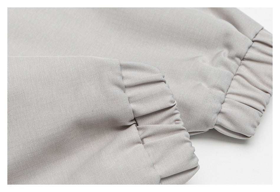 Close-up of a gathered cuff on pale gray fabric.