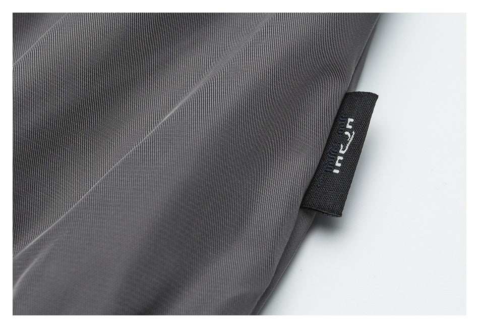 Close-up of gray garment fabric and a small black woven label with lettering.