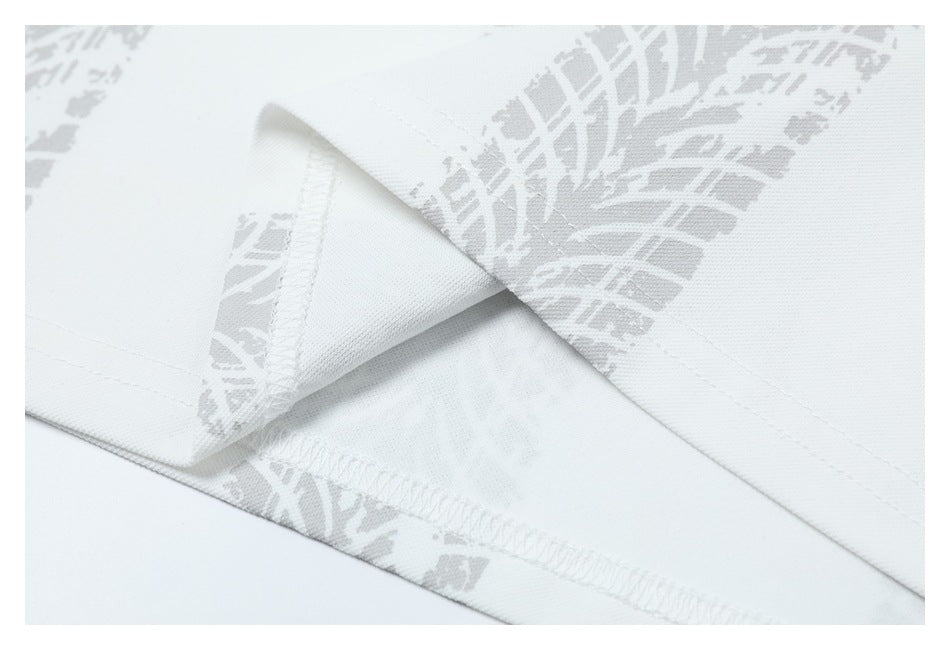 Close-up of a white shirt's folded hem and overlock stitching against a light gray patterned print.