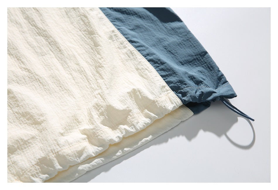 Close-up of the cream and dark blue shirt hem with a gathered edge and adjustable drawcord loop.
