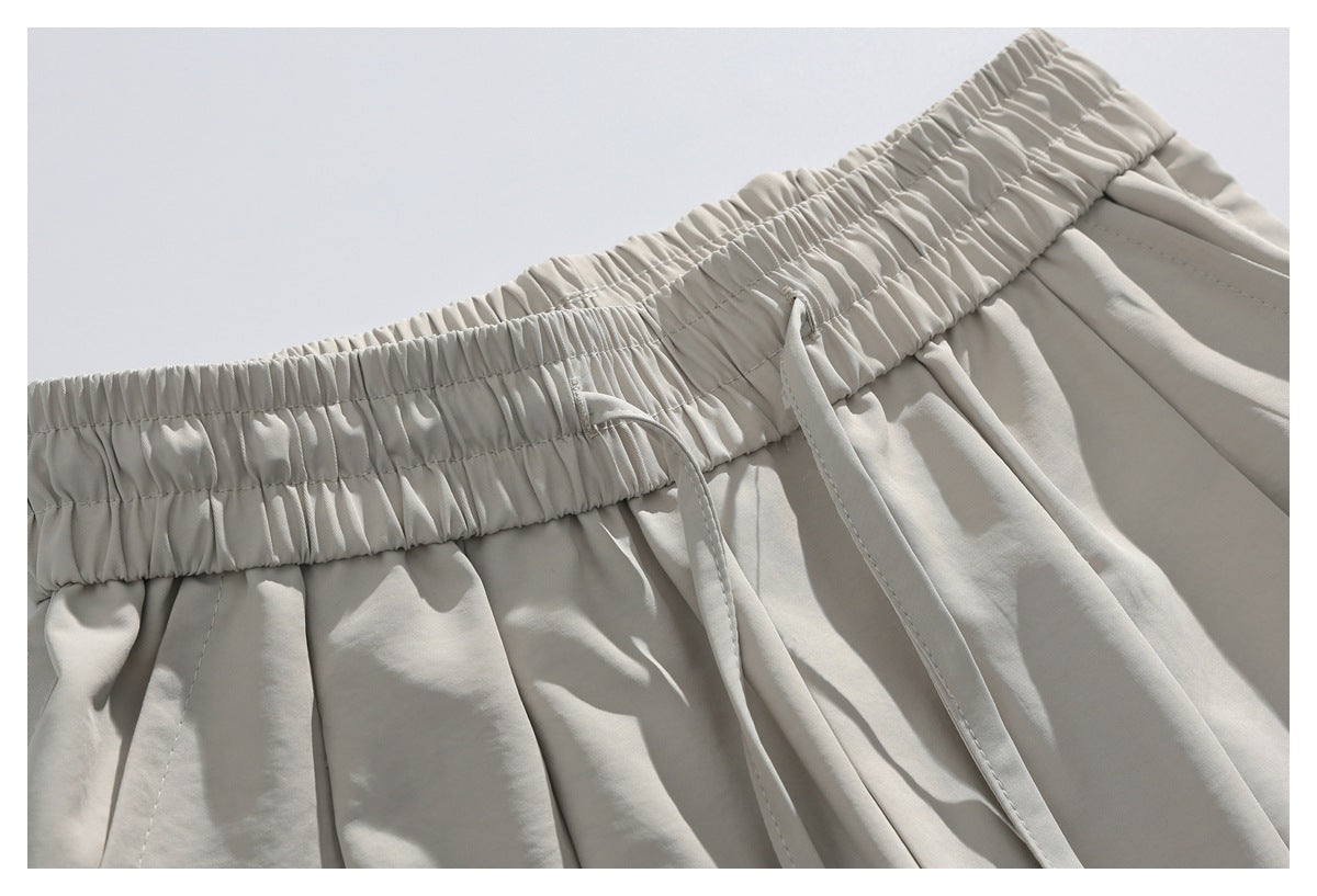 Close-up of light beige trousers showing the gathered elastic waistband and matching drawstrings.