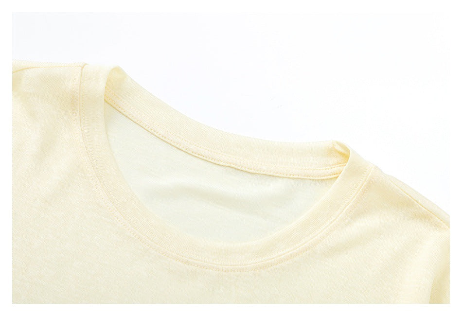 Close-up of the crew neckline and shoulder seam on a pale cream shirt.