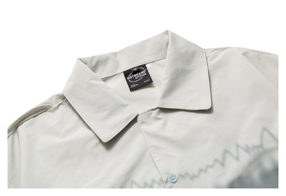 Close-up of an off-white shirt's pointed collar, front placket, and pale blue button.