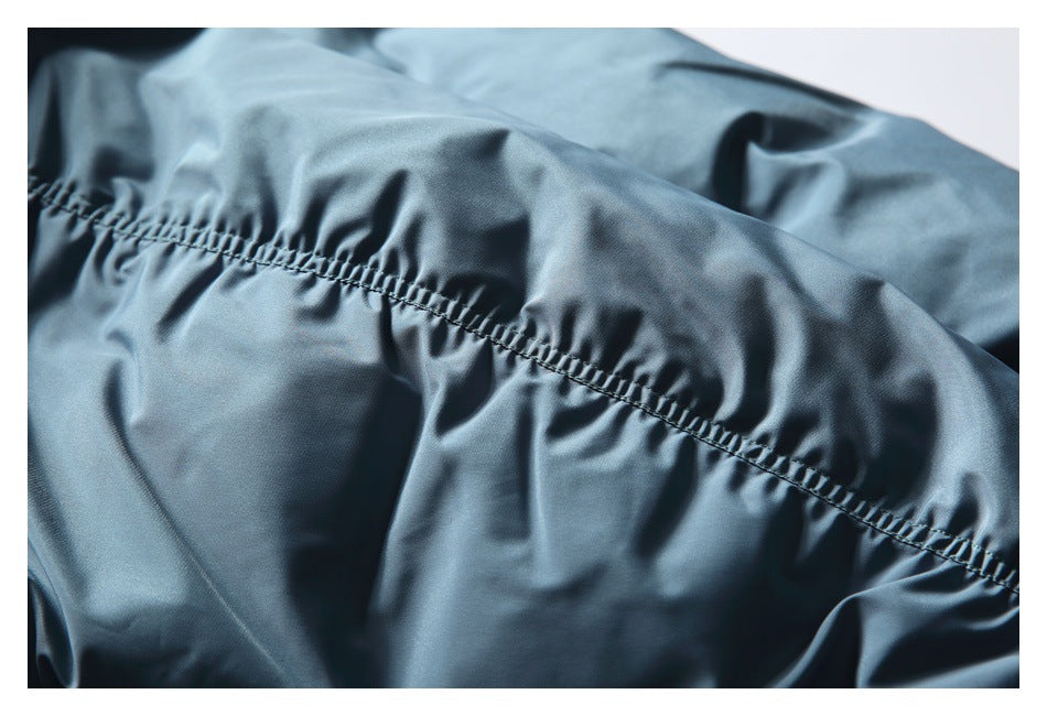 Close-up of blue-gray jacket fabric showing a curved line of gathered stitching.