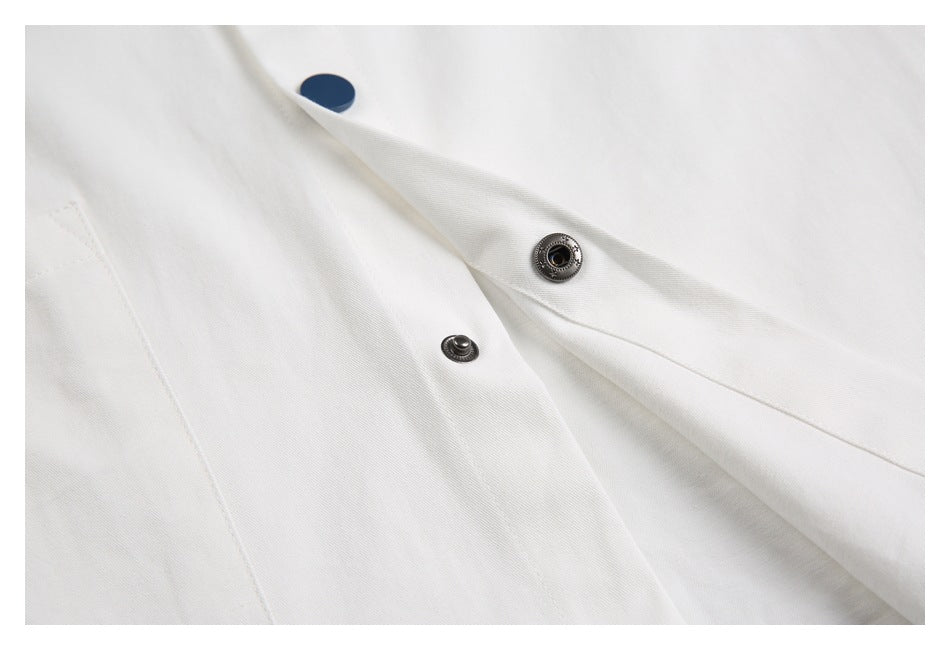 Close-up of the white garment's placket with an open metal snap fastener and dark blue button.
