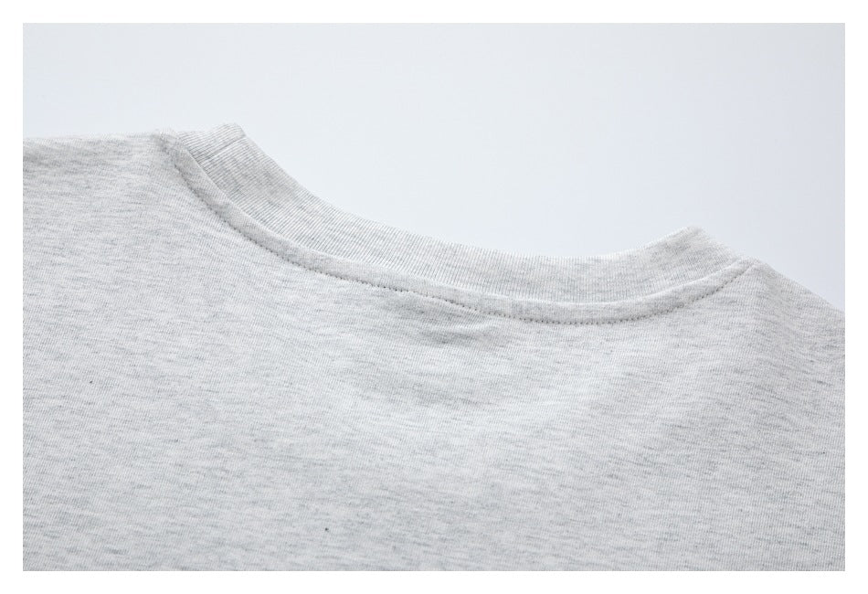Close-up of the ribbed crew neckline and shoulder area of a light gray heather T-shirt.