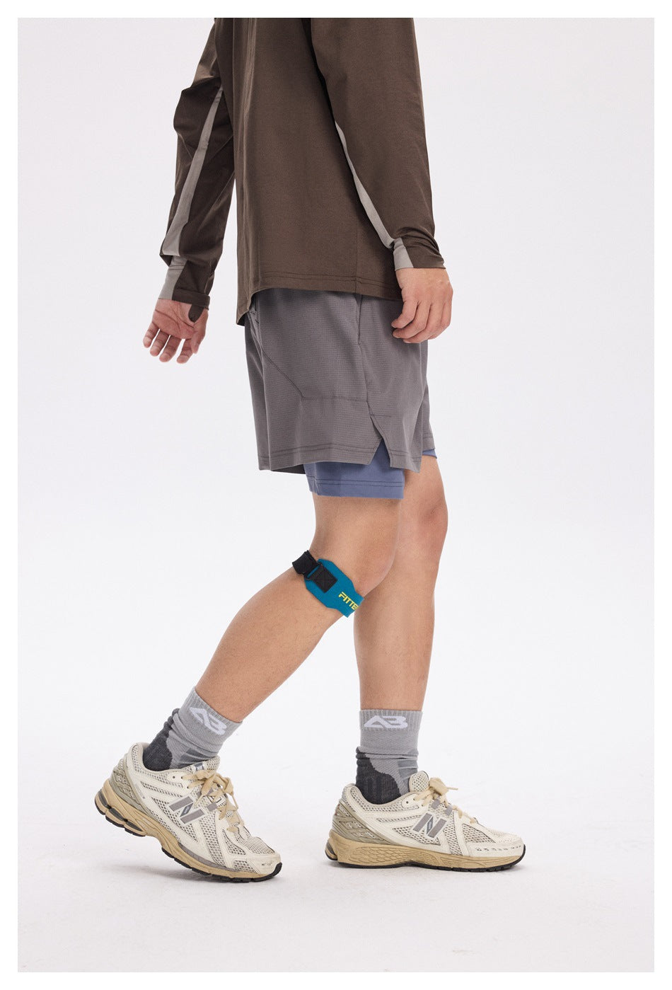 Side view of a model wearing gray running shorts over blue-gray compression shorts.