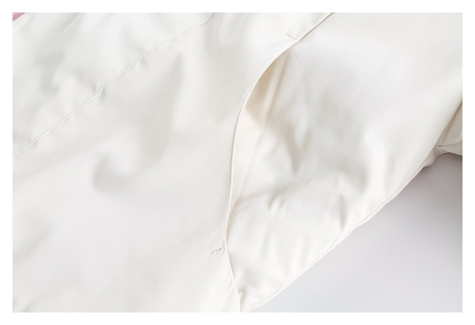 Close-up of the ivory jacket's curved sleeve and body panel seams.