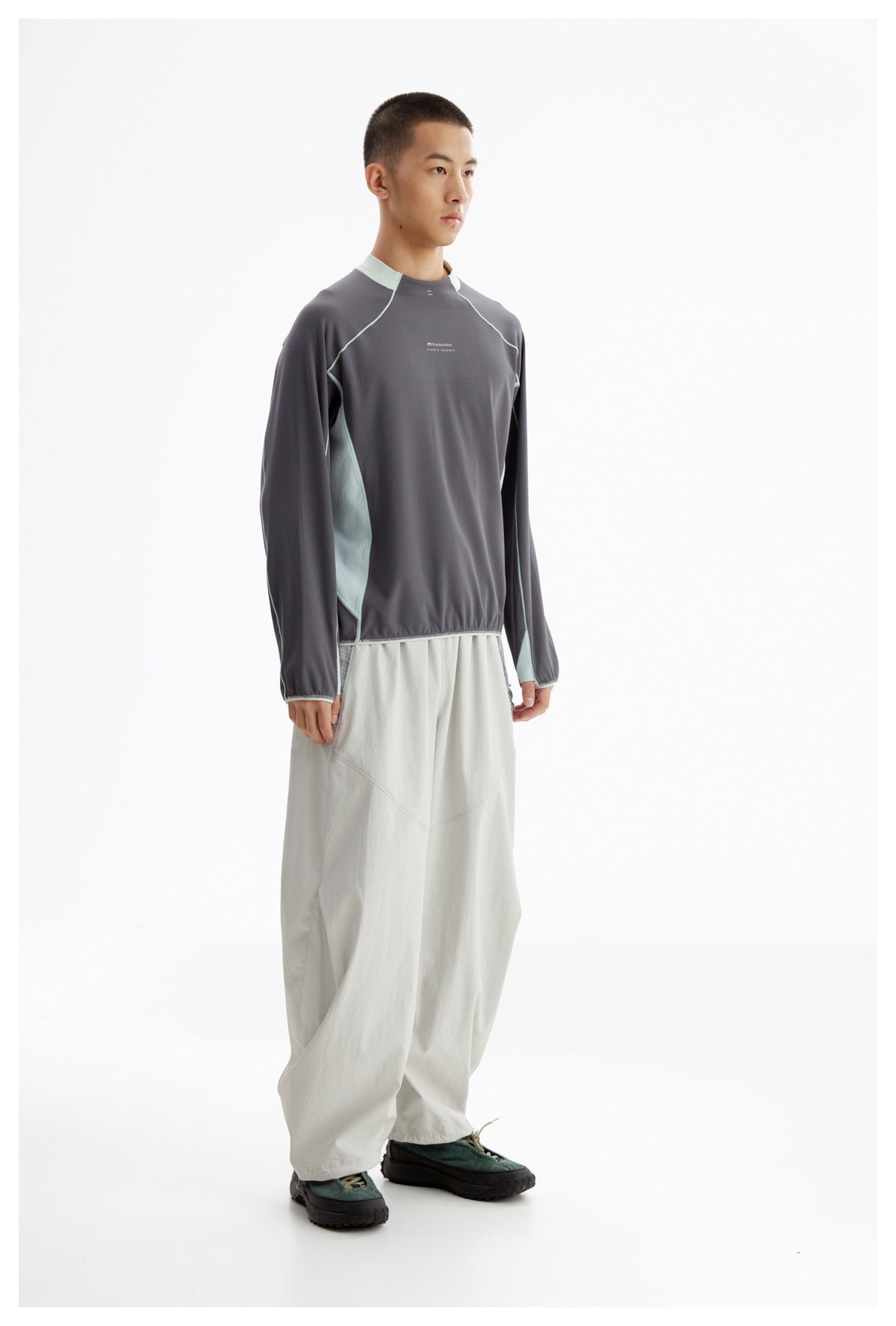 Full-length view of a model wearing a charcoal long-sleeve top with pale mint trim and loose light gray pants.