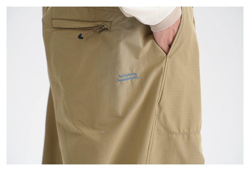 Close-up of khaki pants showing a zippered rear pocket, side pocket, and small blue garment text.