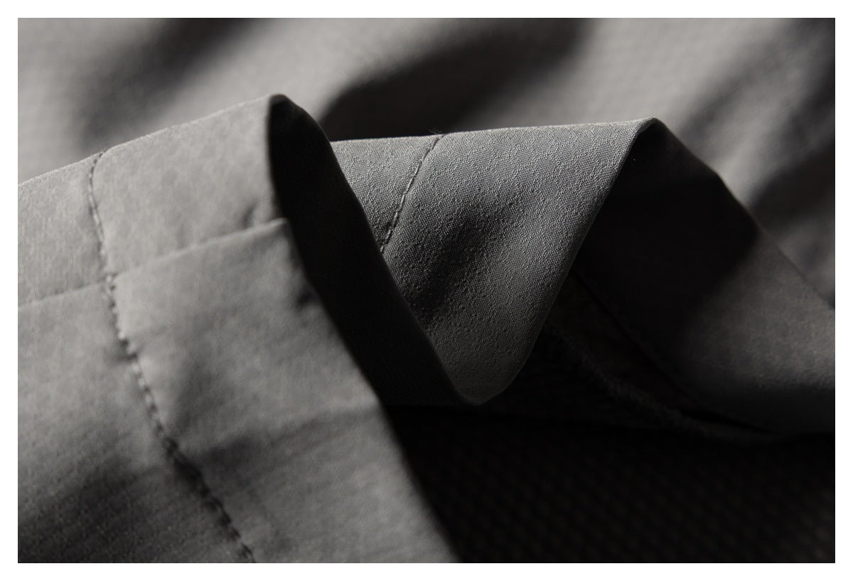 Close-up of gray trouser fabric showing a folded, stitched edge and dark textured lining.