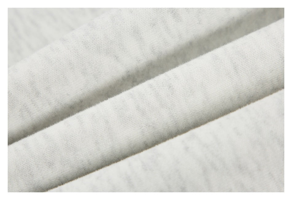 Extreme close-up of the light gray marled garment fabric and folded edge.