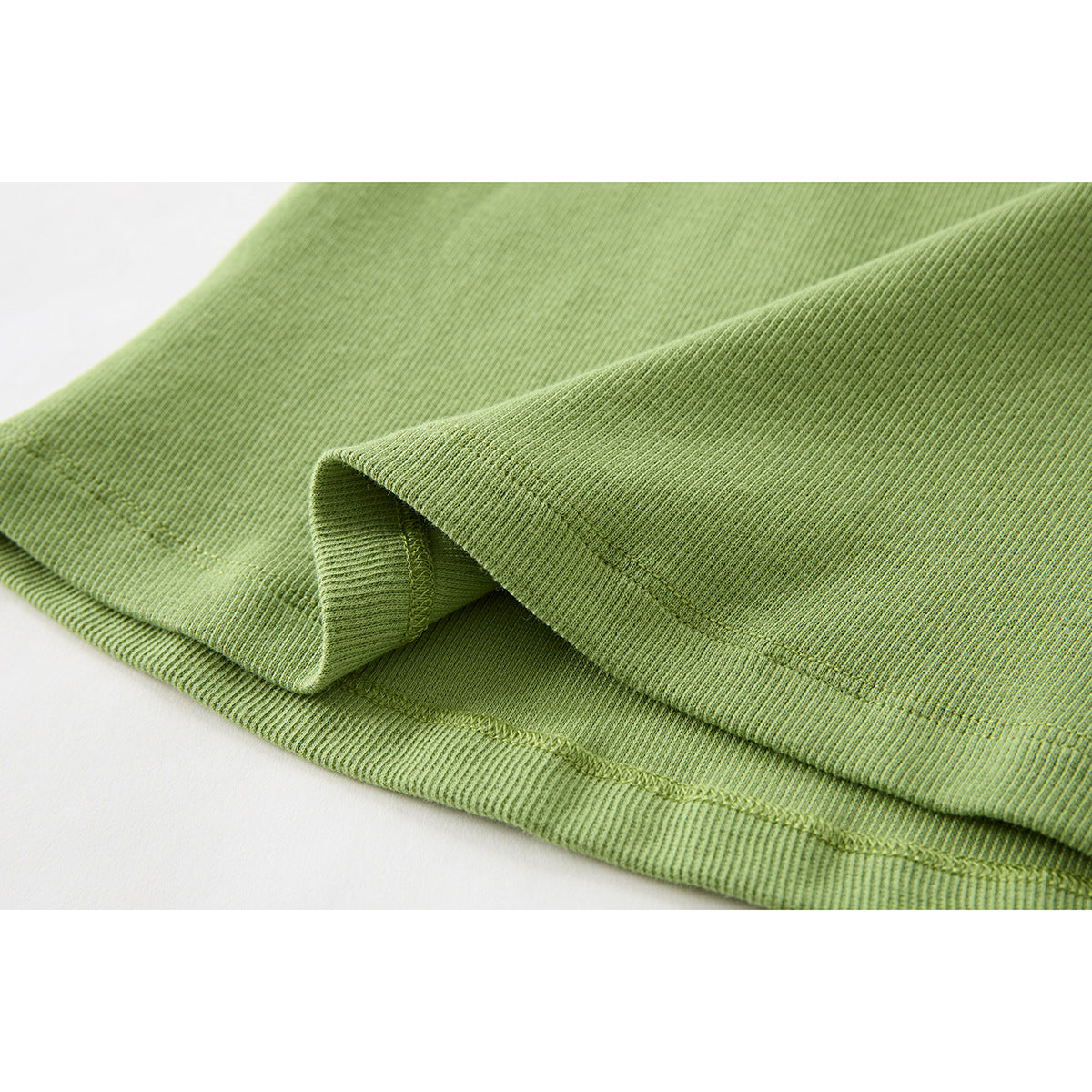 Close-up of the light green ribbed tank top’s folded hem and stitching.