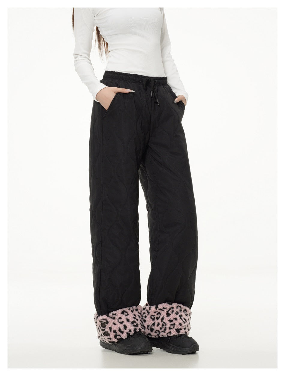 Cropped model wearing black quilted wide-leg pants with a drawstring waist and pink leopard-print ankle cuffs.