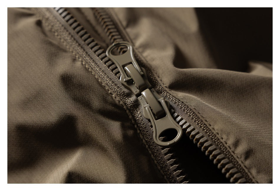 Close-up of a double-pull zipper on olive-brown garment fabric.