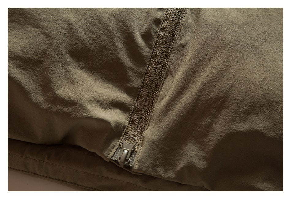 Close-up of the lower end of a zipper on olive-khaki garment fabric.