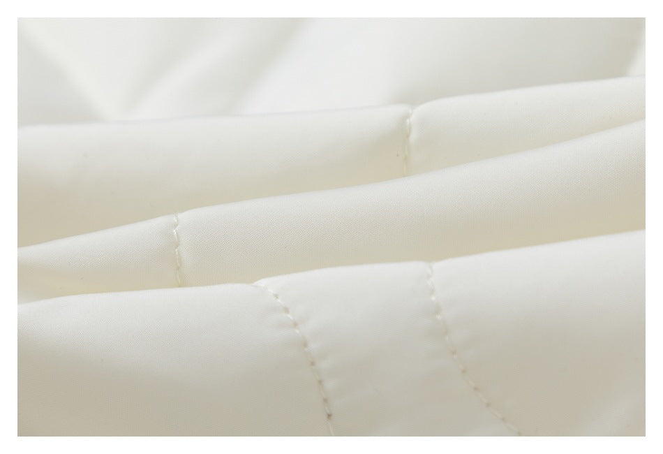 Close-up of cream-colored fabric showing padded sections and stitched seams.