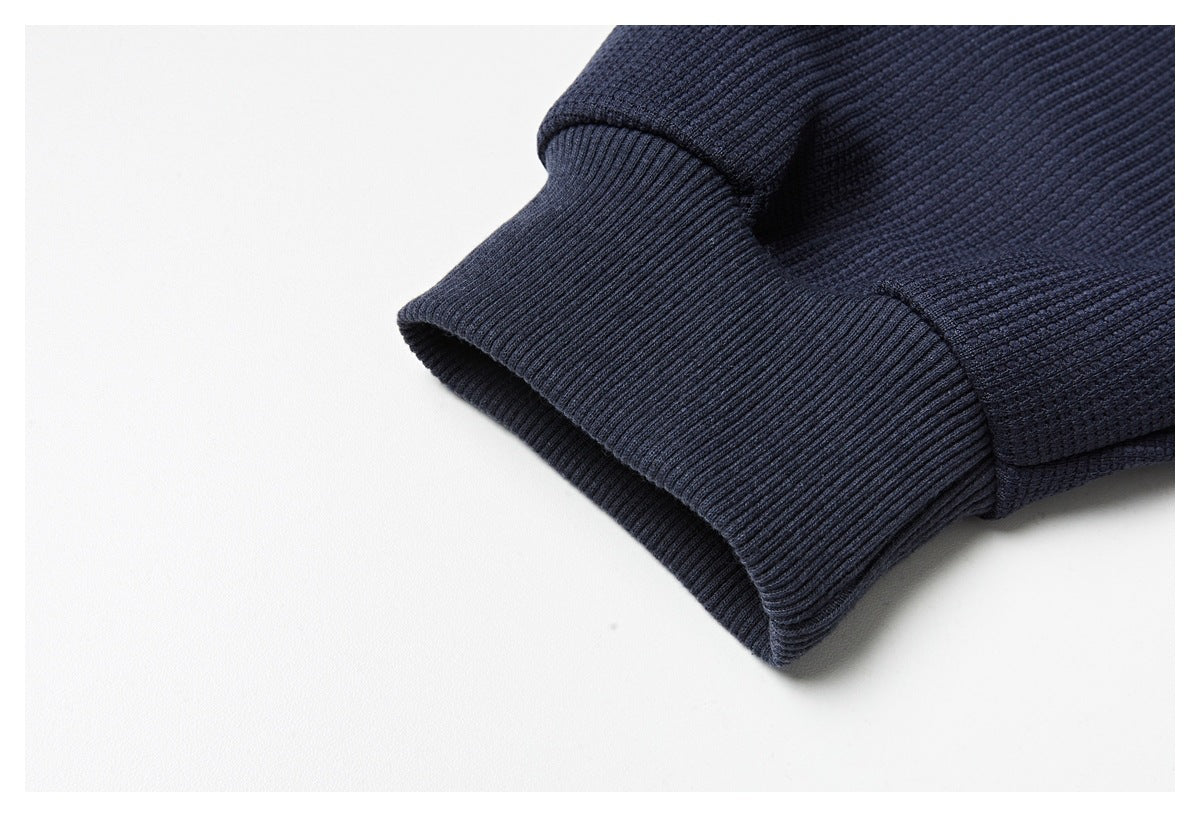 Close-up of the navy sweatshirt's ribbed cuff and textured sleeve fabric.