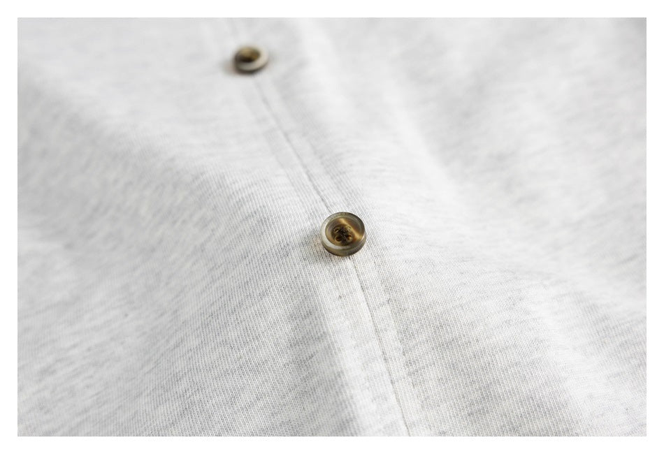 Close-up of two brown buttons along the front placket of a light gray shirt.