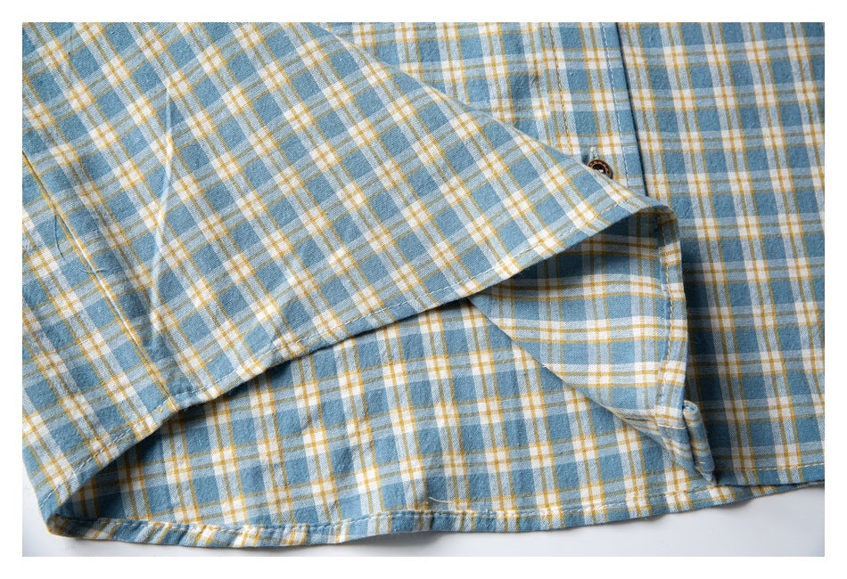 Close-up of a blue, white, and mustard plaid shirt showing the collar, button placket, and hem stitching.