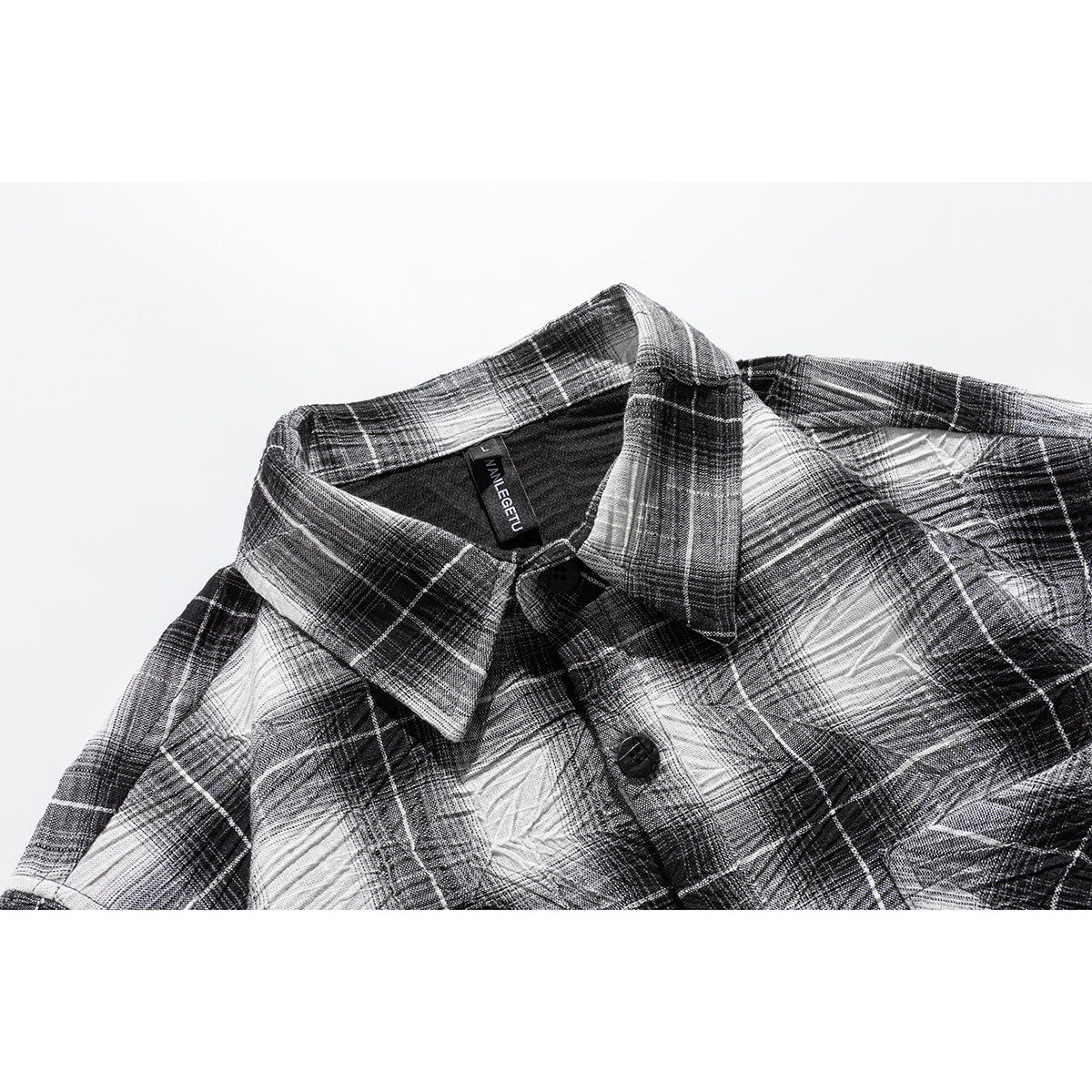 Close-up of a black, gray, and white plaid shirt collar, neckline, and front button.