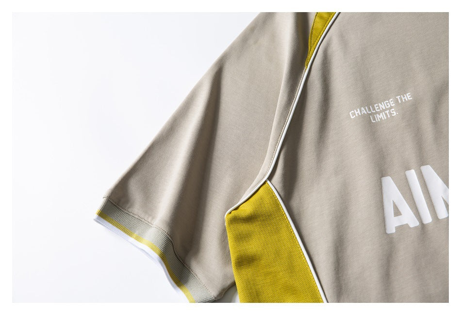 Close-up of a beige shirt sleeve and yellow side panel with white piping and printed lettering.