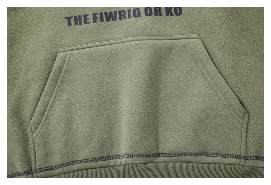 Close-up of the olive green hoodie’s front kangaroo pocket and dark printed lettering above it.