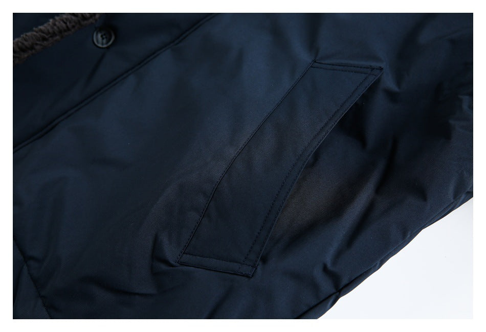 Close-up of a dark navy garment with a slanted welt pocket, button, and fuzzy trim.