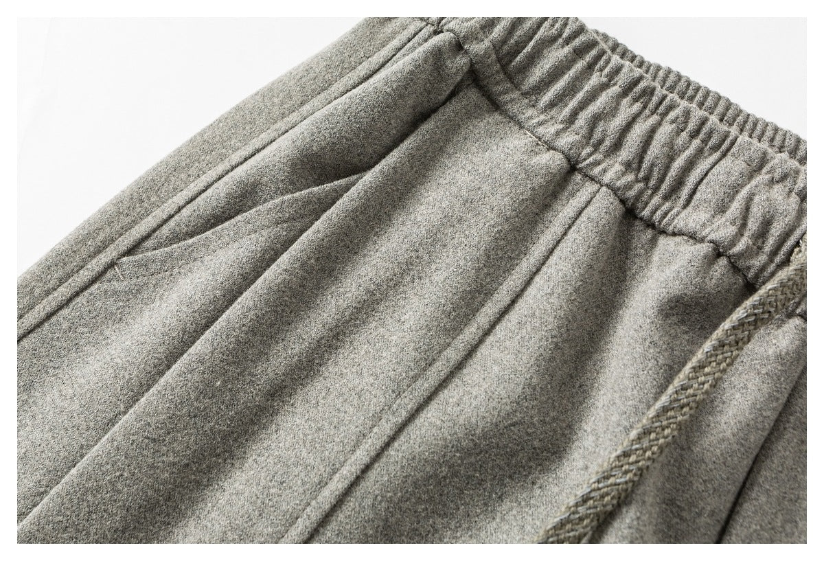 Close-up of light gray pants showing the elastic waistband, a braided drawstring, and front seams.