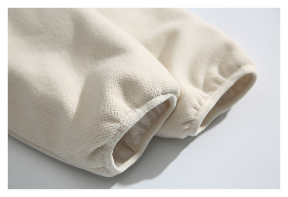 Close-up of ivory textured garment fabric and two bound openings.