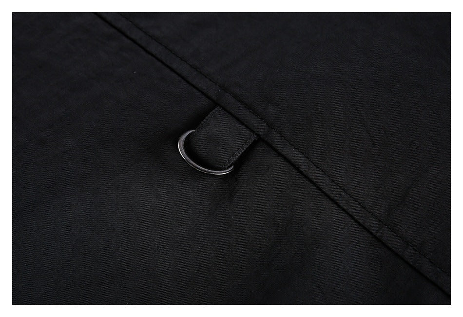 Close-up of a black garment showing a metal D-ring attached to a stitched fabric tab.