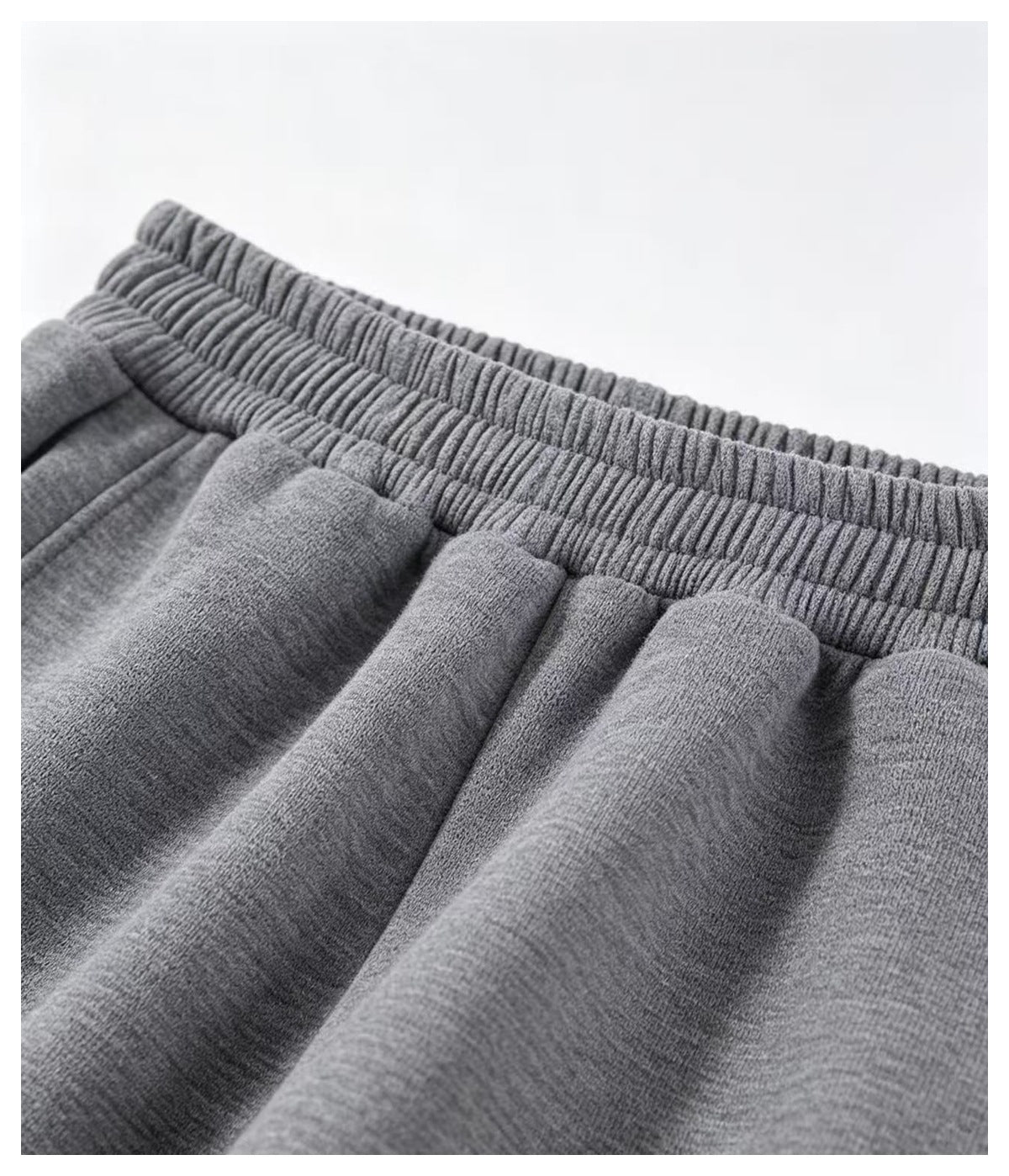 Close-up of the gray pants' gathered elastic waistband and front pleats.