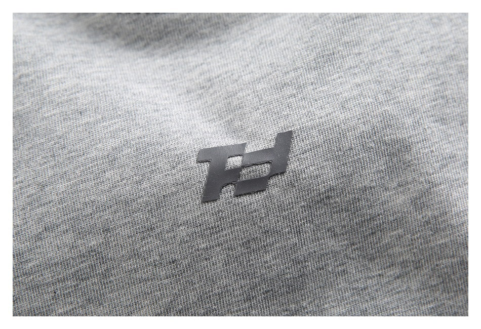 Close-up of a small dark emblem on heather gray knit fabric.