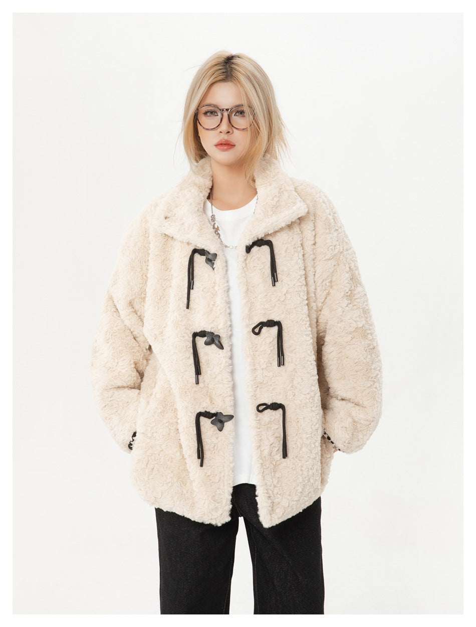 Cropped front view of a model wearing an ivory textured coat with black toggle closures.