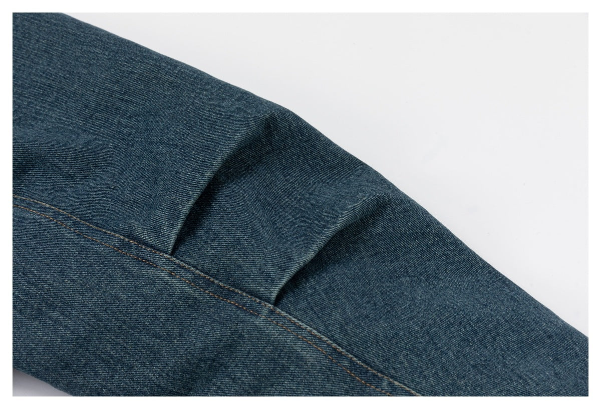 Close-up of a curved stitched seam on a blue denim jacket.
