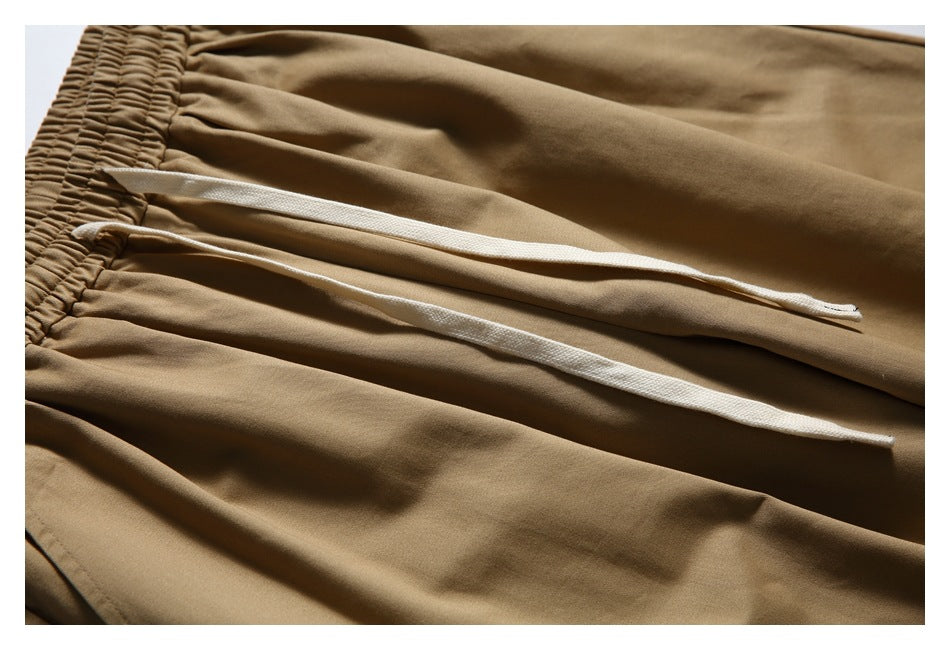 Close-up of tan trousers with white drawstrings emerging from the gathered waistband.