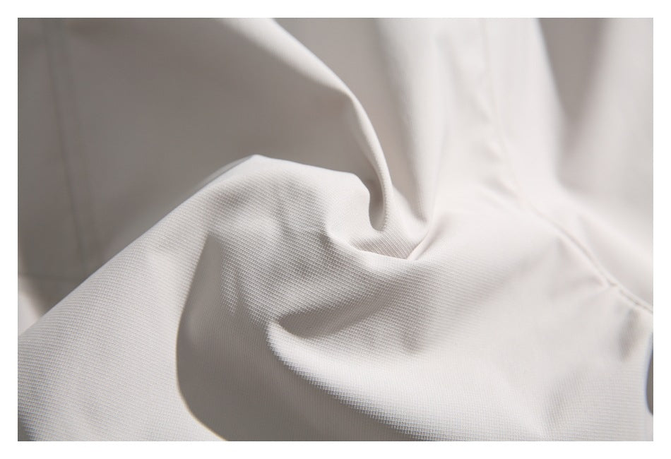 Close-up of off-white garment fabric showing its fine texture and soft folds.