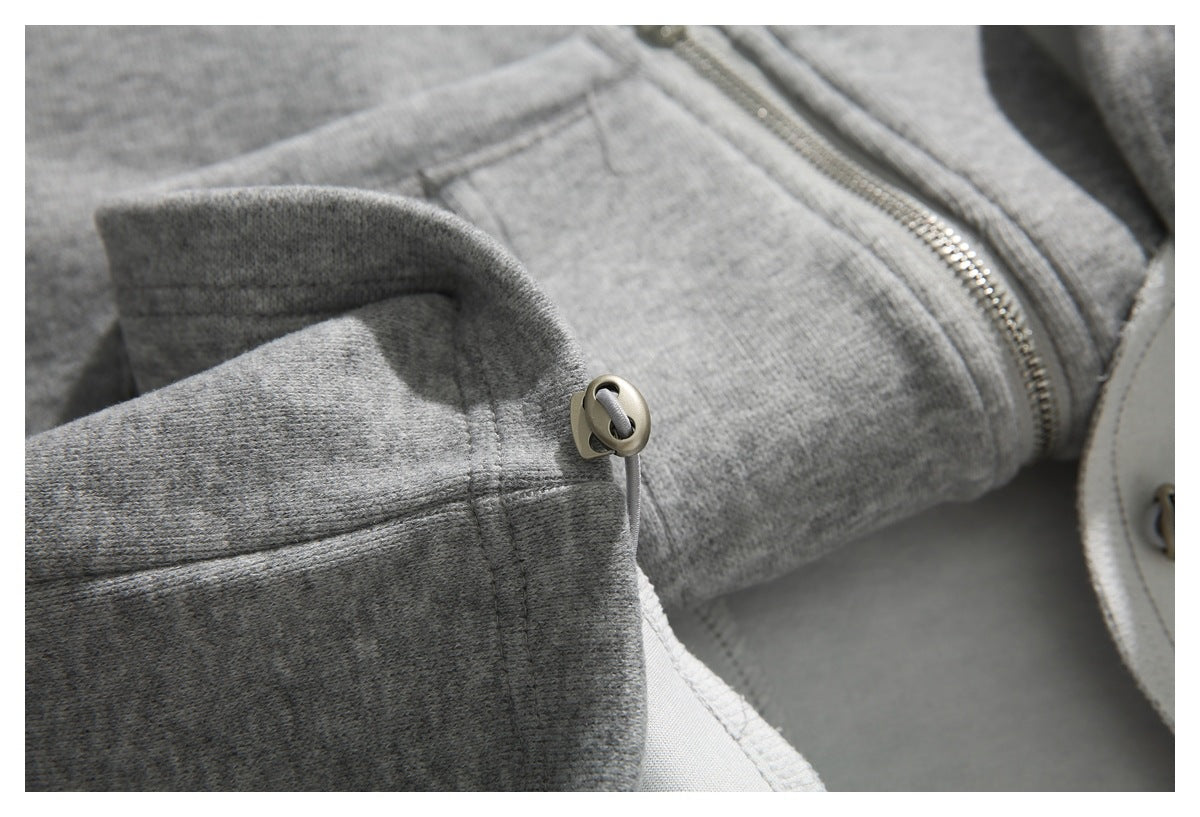 Close-up of a gray drawcord and round stopper beside a garment seam and zipper.