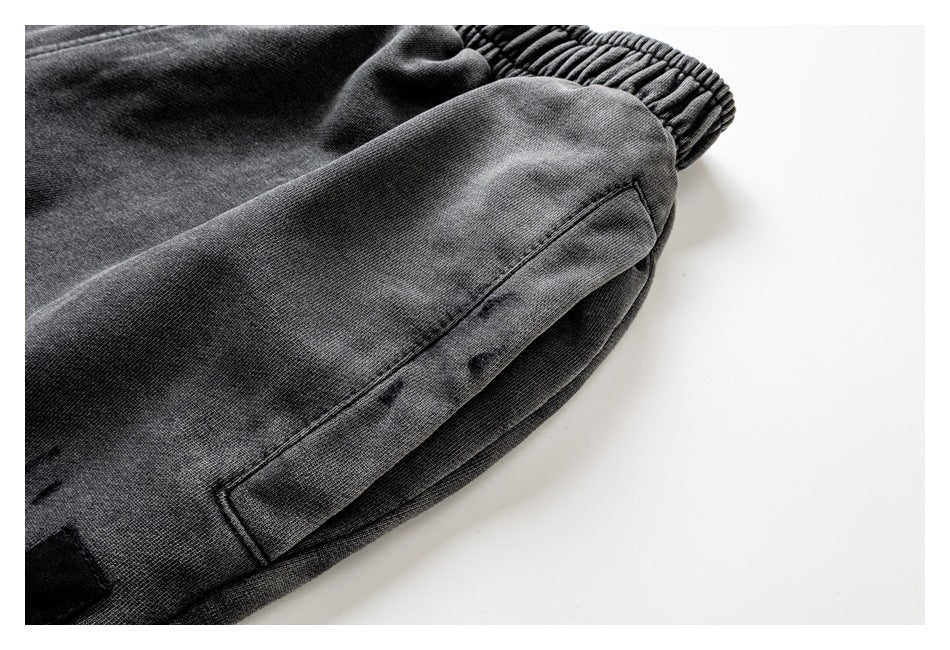 Close-up of charcoal-gray pants showing a stitched side pocket and elastic ankle cuff.