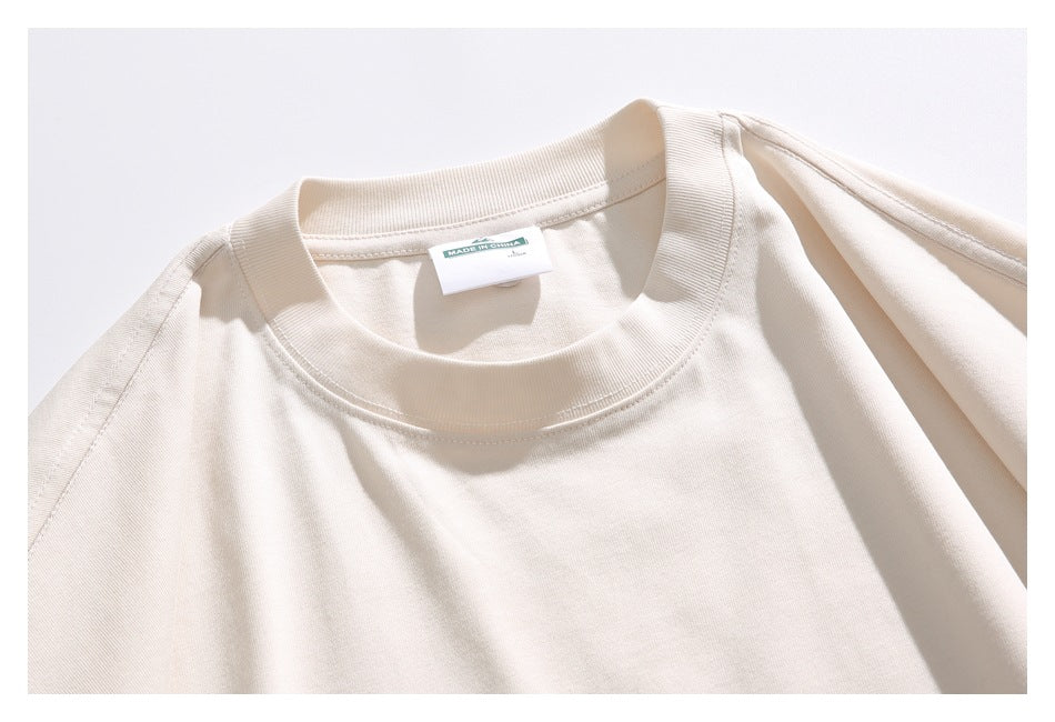Close-up of the cream T-shirt’s ribbed crew neck and inner neck label.