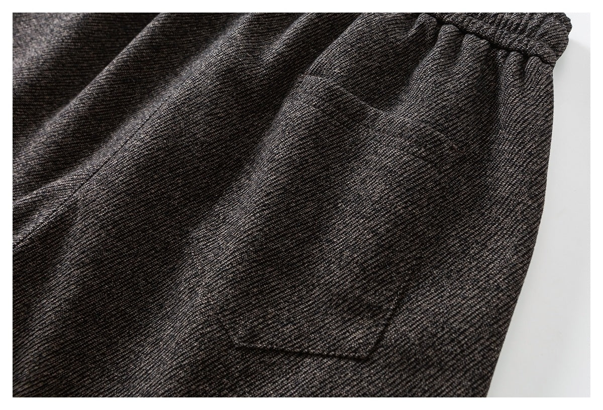 Close-up of a patch pocket on charcoal gray marled pants, with the gathered waistband visible above.