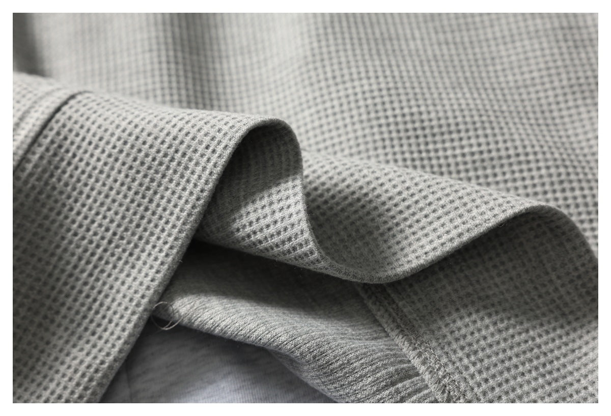 Close-up showing the folded edge, inner seam, and waffle texture of a gray garment.