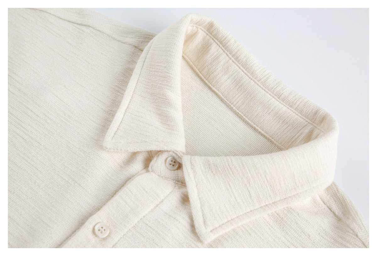 Close-up of an ivory textured garment's pointed collar and two matching buttons.
