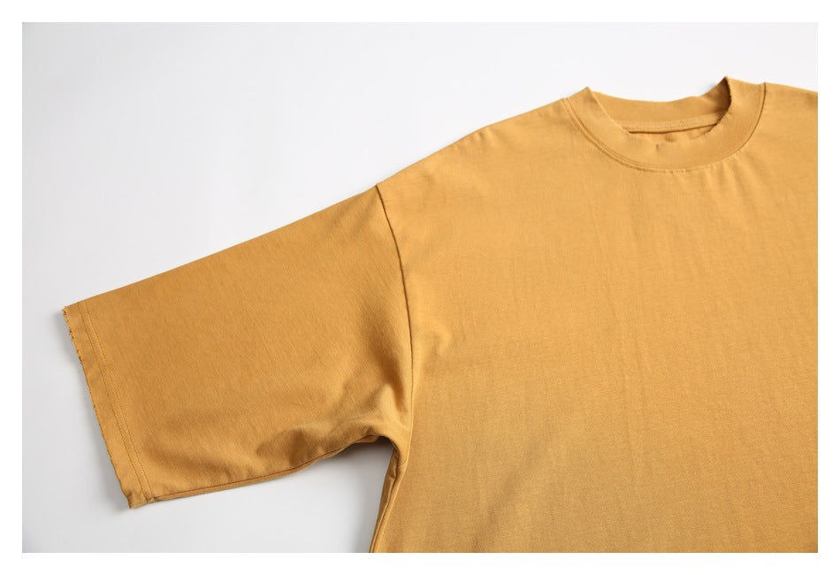 Partial front view of an ochre short-sleeve crew-neck T-shirt laid flat on a white background.