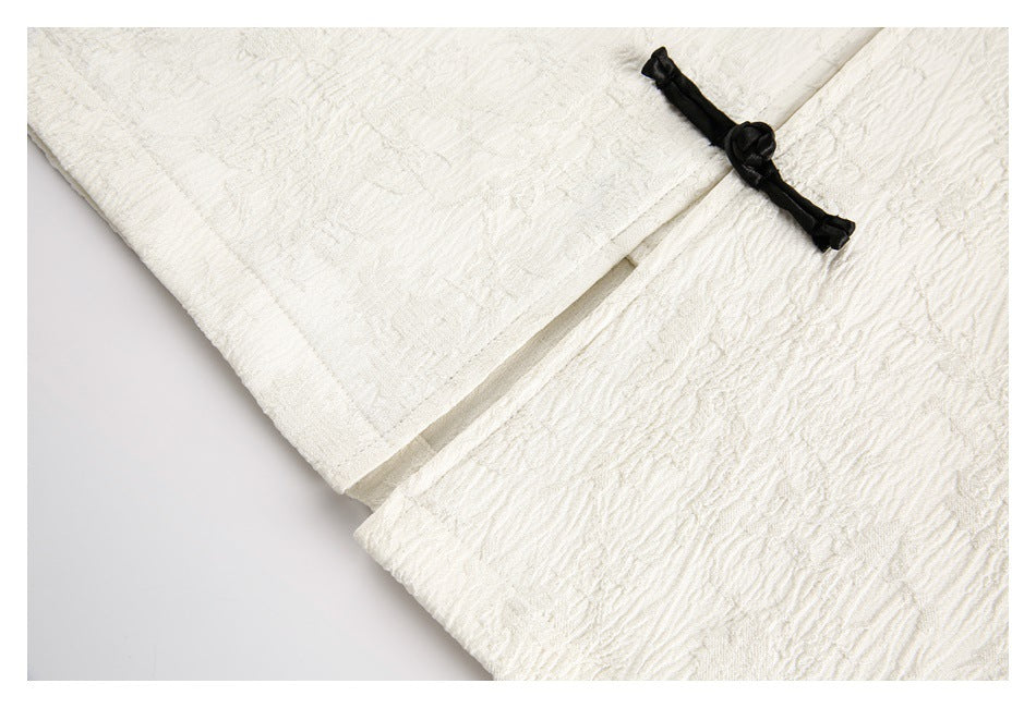 Close-up of an ivory textured garment with a black knotted frog closure.